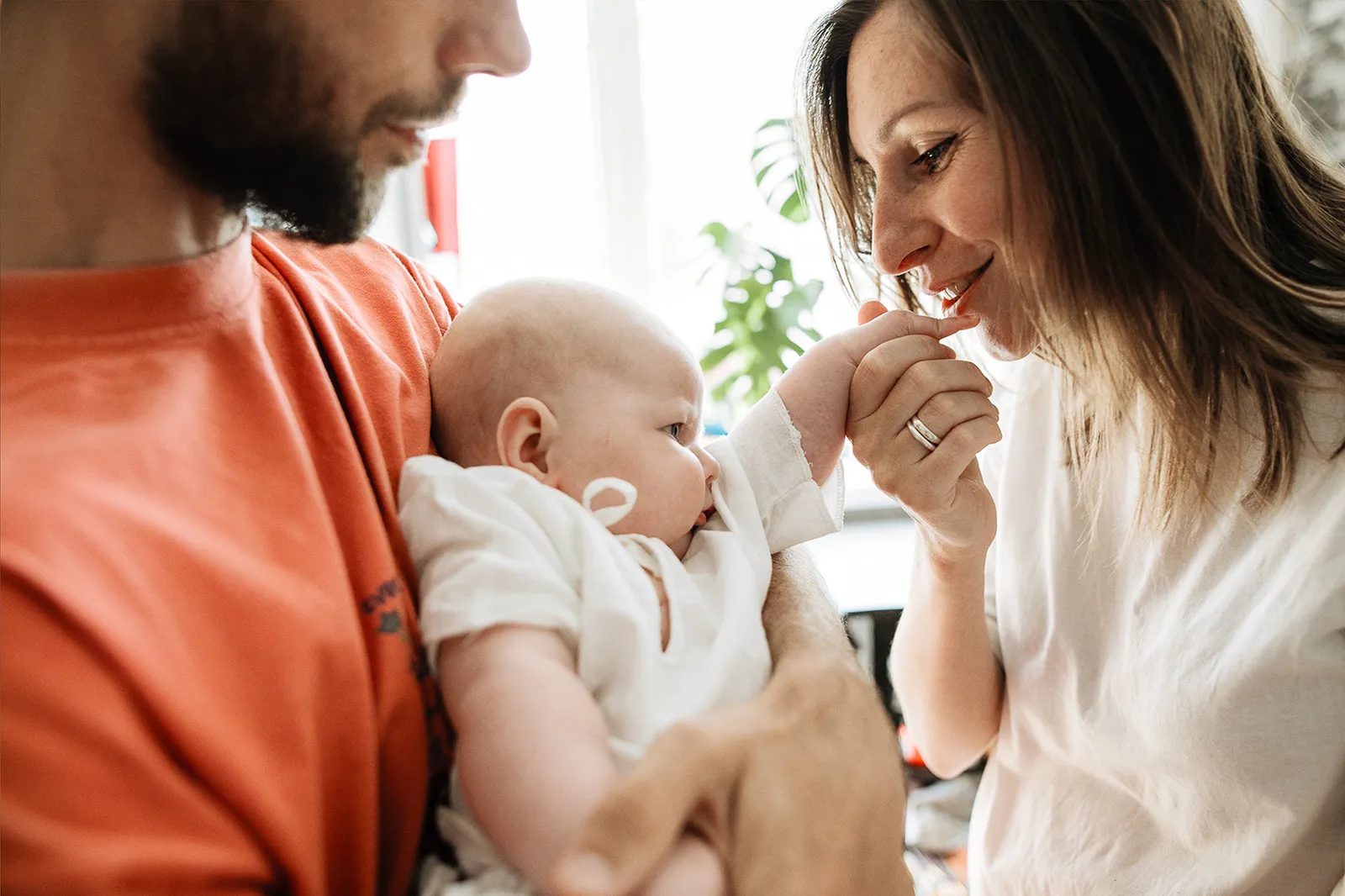 I genitori tengono in braccio il loro bambino e gli sorridono.