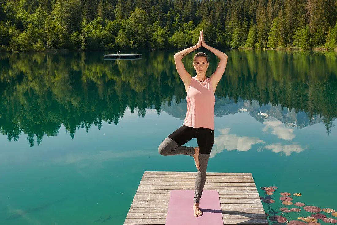 Frau macht Yoga auf einem Steg an einem wunderschönen Bergsee
