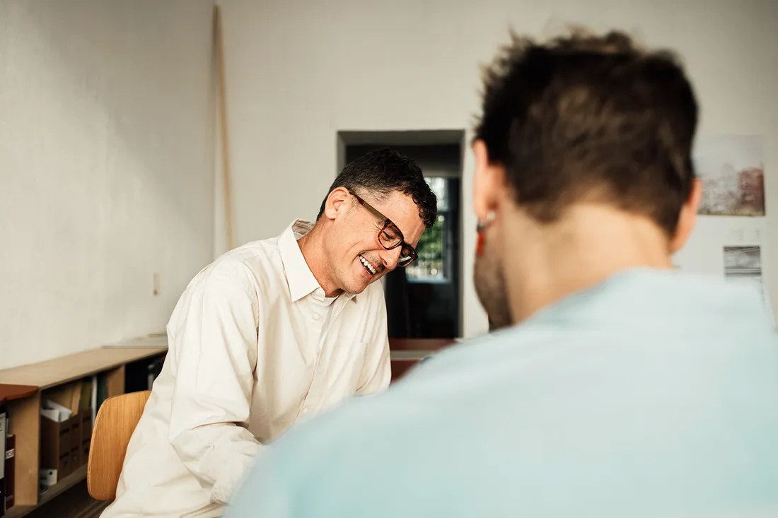 Due uomini sono seduti a un tavolo e parlano tra loro.