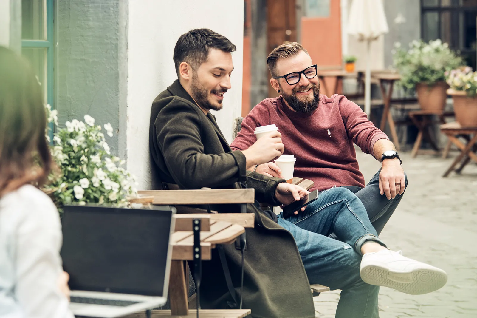 Due uomini sono seduti in un bar all’aperto e bevono caffè.