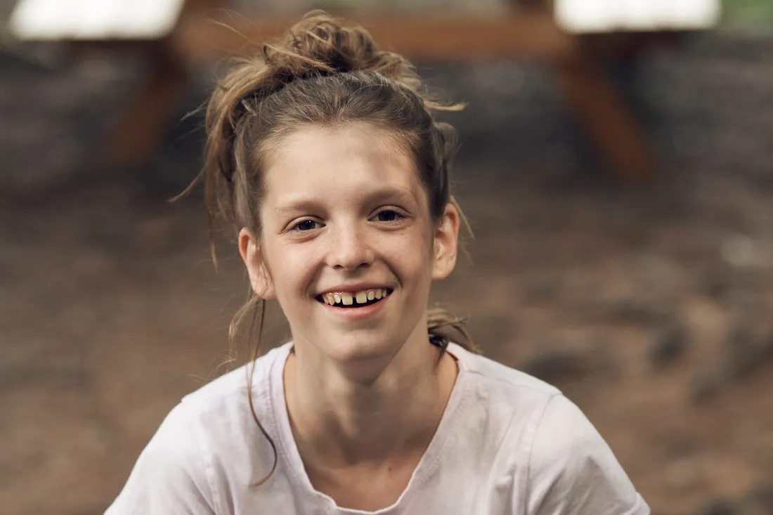 Una ragazza sorride alla fotocamera all’aperto.