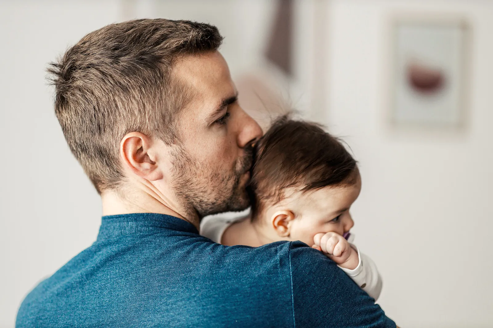 Un padre tiene in braccio il suo bambino e gli bacia la testa.