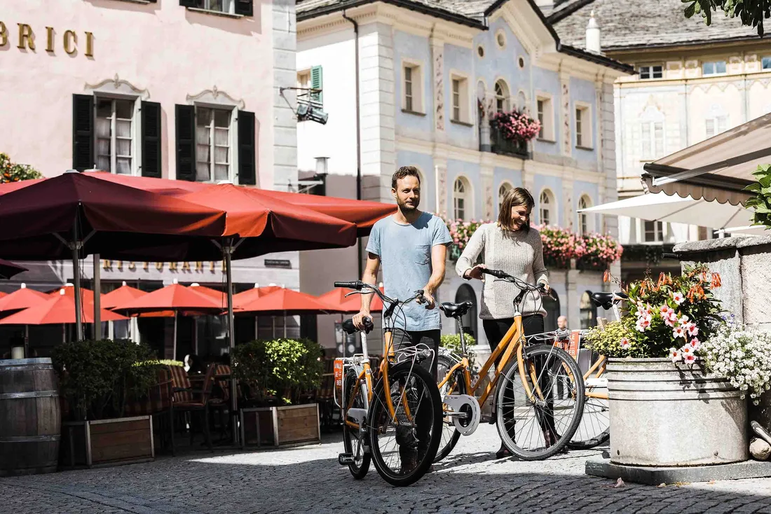 Paar schiebt Fahrräder durch eine malerische Altstadt