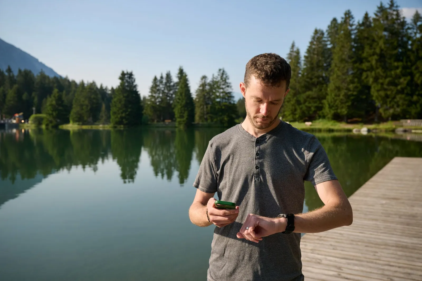 Mann hält Smartphone in der Hand und sieht auf seine Smartwatch