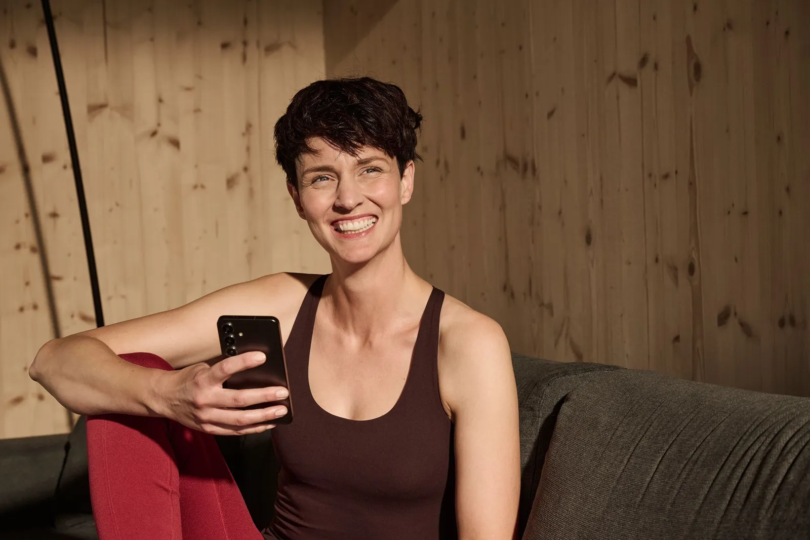 Person mit Smartphone in einem Wohnraum mit Holzverkleidung.