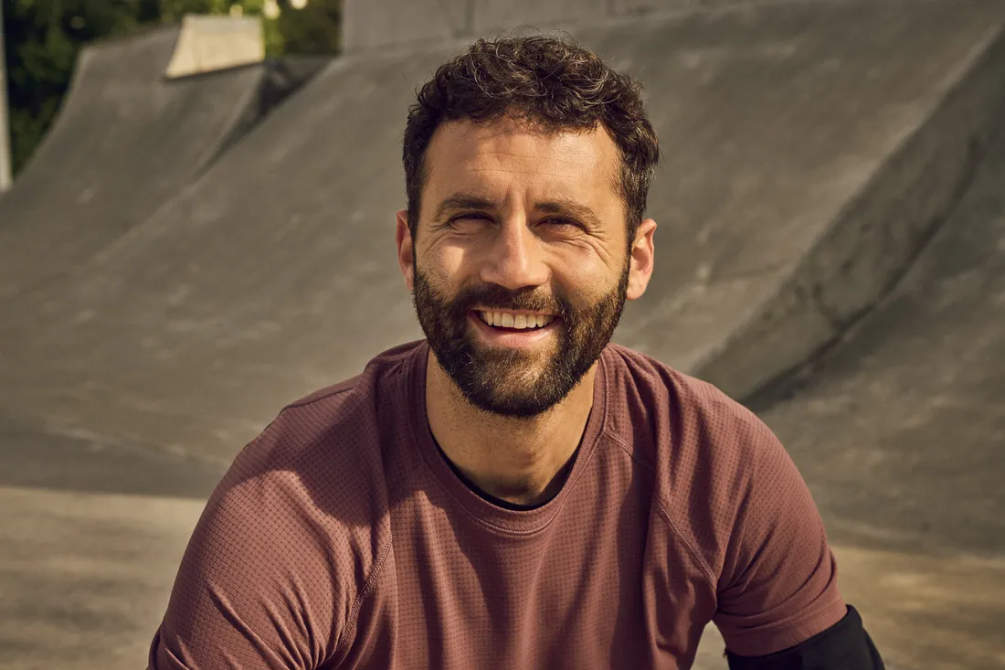 Una persona è seduta in uno skatepark e guarda verso la fotocamera.