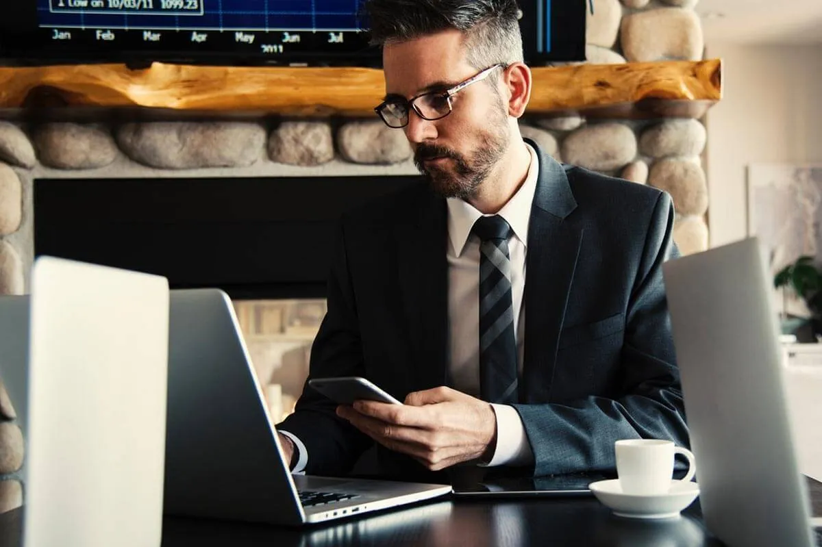 Mann mit Anzug, Smartphone und Laptop