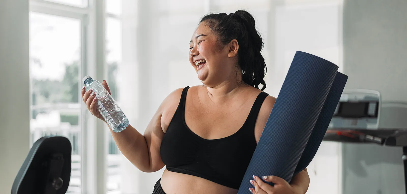 Plus size Asian woman exercises in gym. Beautiful overweight woman in sportswear smiling and happy in fitness. concept of body positive, self-acceptance, weight loss.
