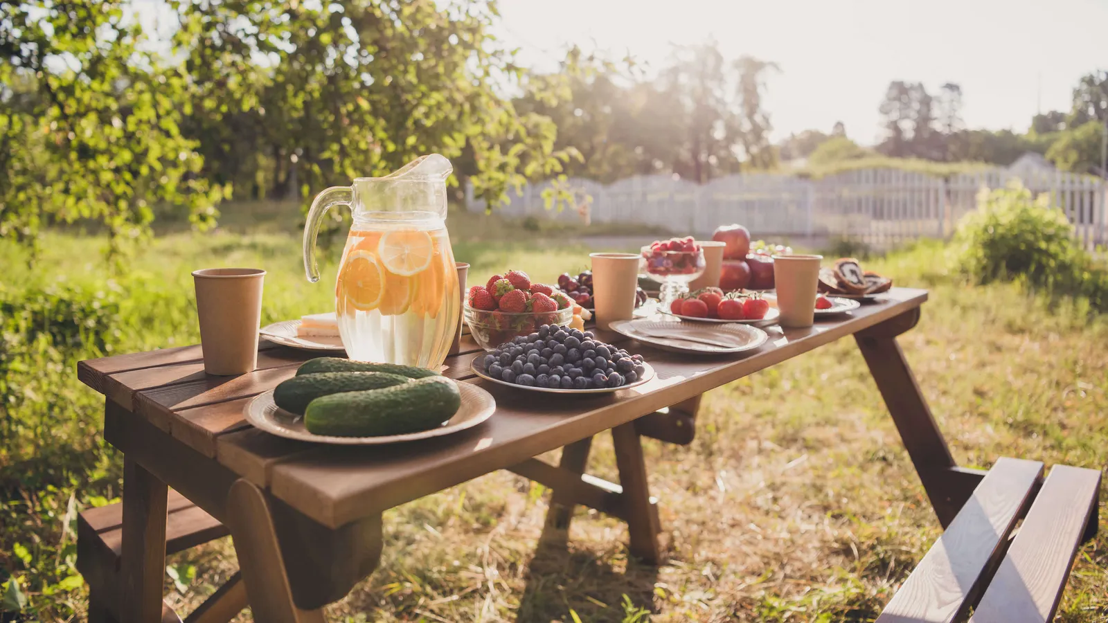 Picknicktisch ist reich gedeckt mit Gemüse, Früchten und Getränken