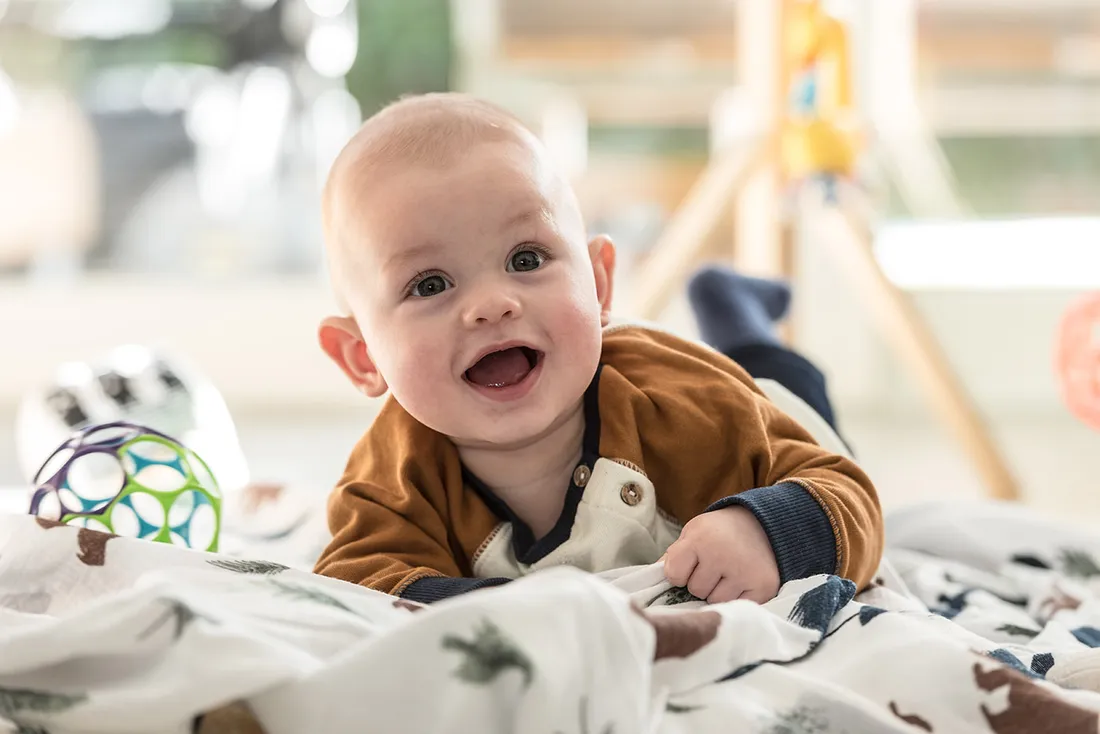 Lachendes Baby liegt auf einer Decke