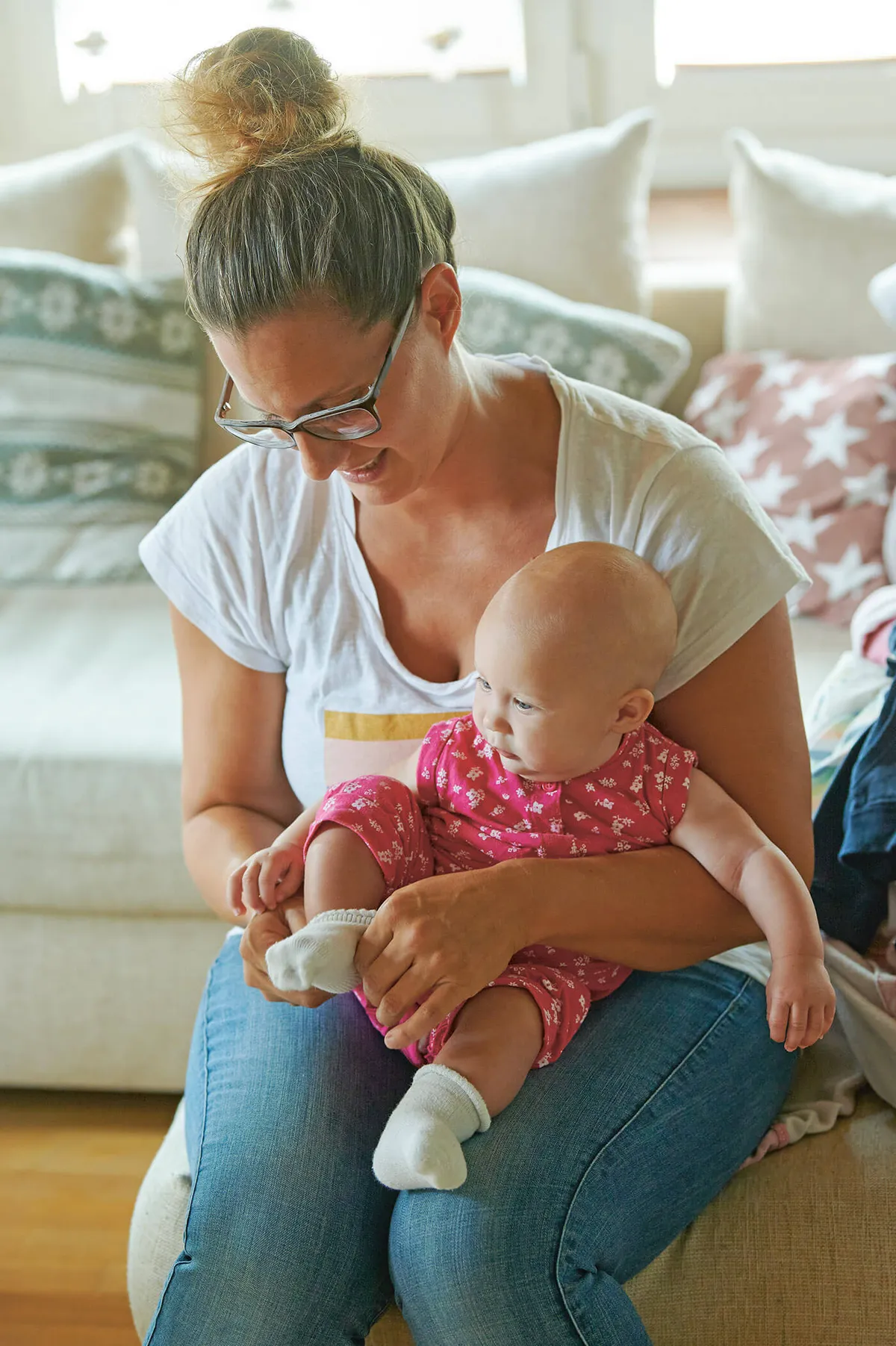 Junge Mutter, die eine Geburt während Corona hatte, zieht ihrer Tochter Socken an