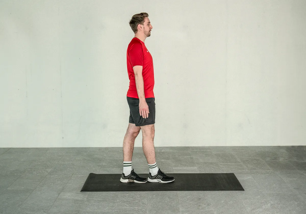 Ein junger Mann trainiert sein Gleichgewicht, indem er den Liniengang auf der Yogamatte übt.