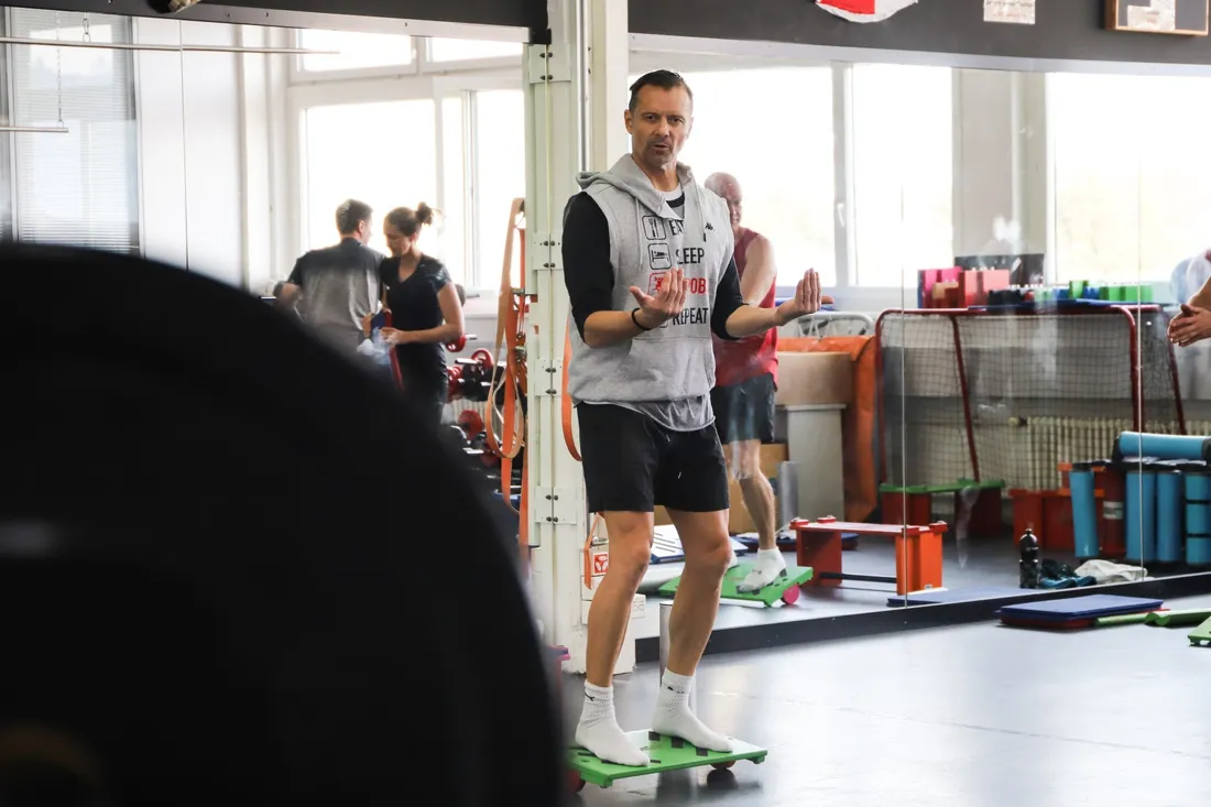 Robin Städler balanciert auf einem Sypoba Balance Board in einem Fitnessstudio mit Trainingsgeräten im Hintergrund