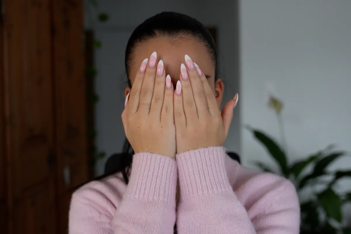 Person mit geschlossenen Augen, die ihre Hände über das Gesicht hält, um eine Palmier-Übung zur Stressreduktion durchzuführen.