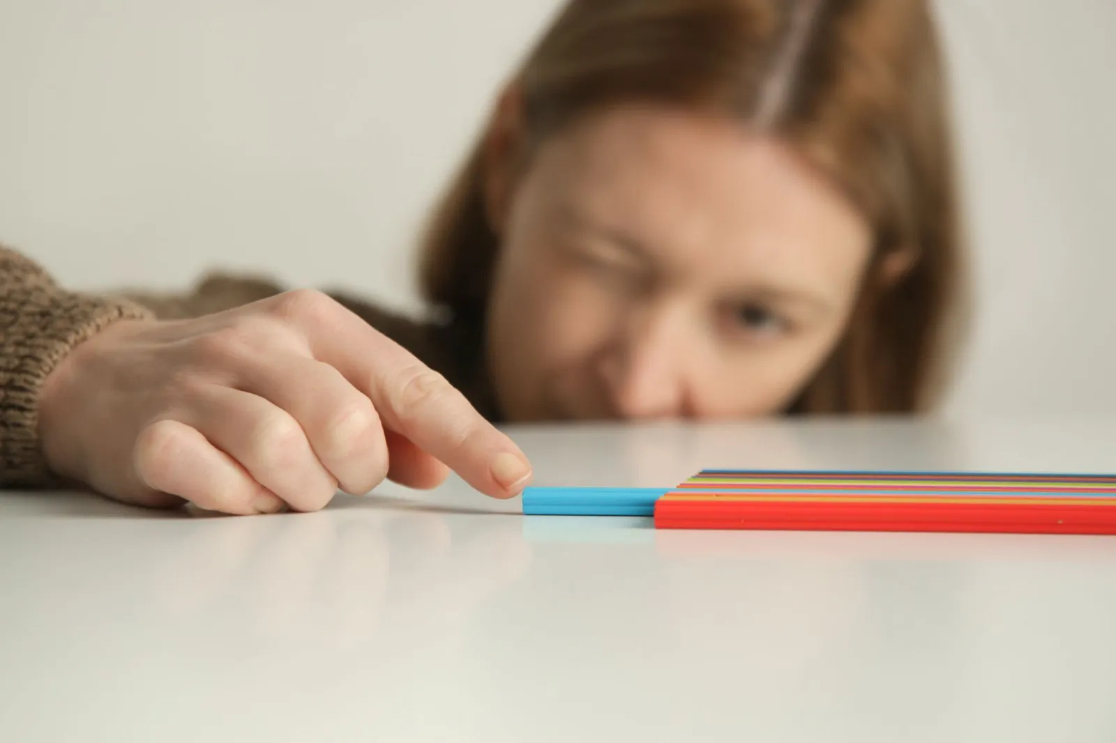 Frau richtet zwei Stifte, einen blauen und einen roten, auf einer weißen Oberfläche aus