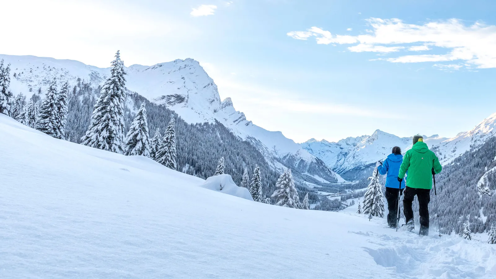 Paar wandert mit Schneeschuhen durch die tief verschneite Winterlandschaft Graubündens
