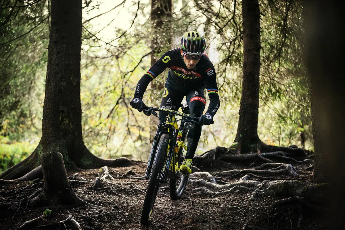 Nino Schurter auf einem Wurzeltrail im Wald