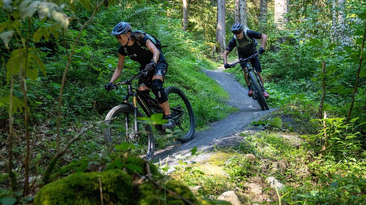 Zwei Biker auf einem Singletrail im Wald
