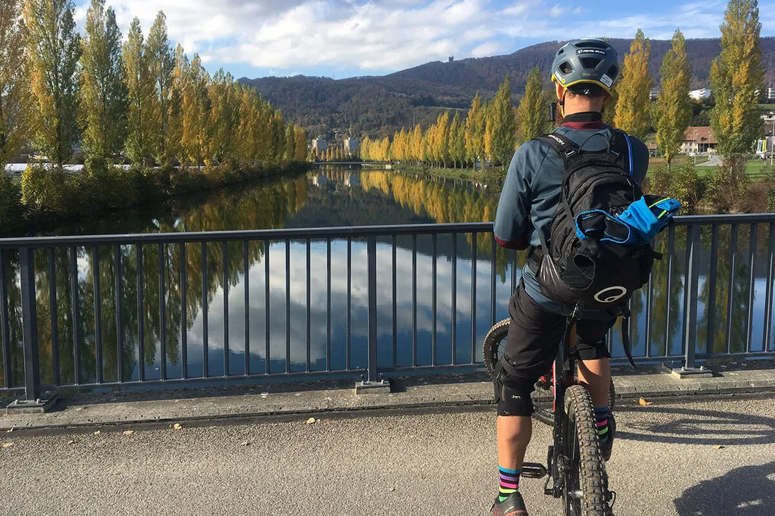 Mountainbiker steht auf einer Brücke und blickt auf die Aare