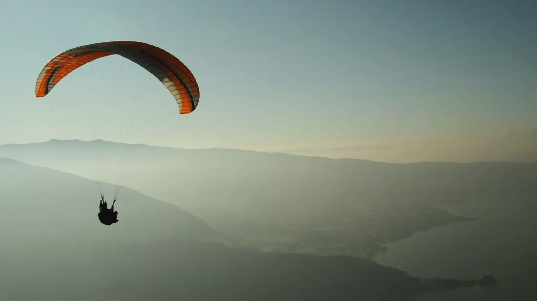 Person fliegt mit einem Gleitschirm hoch in der Luft