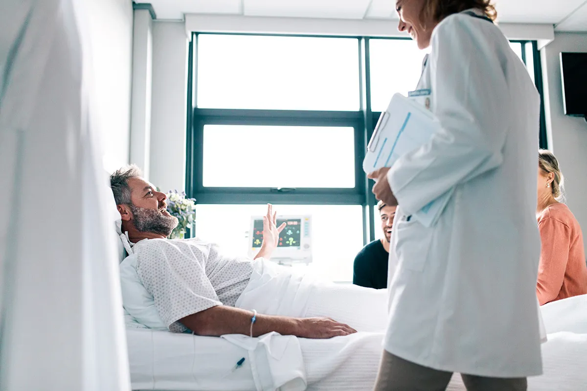 Paziente in ospedale parla con una dottoressa – vantaggio di un’assicurazione ospedaliera.