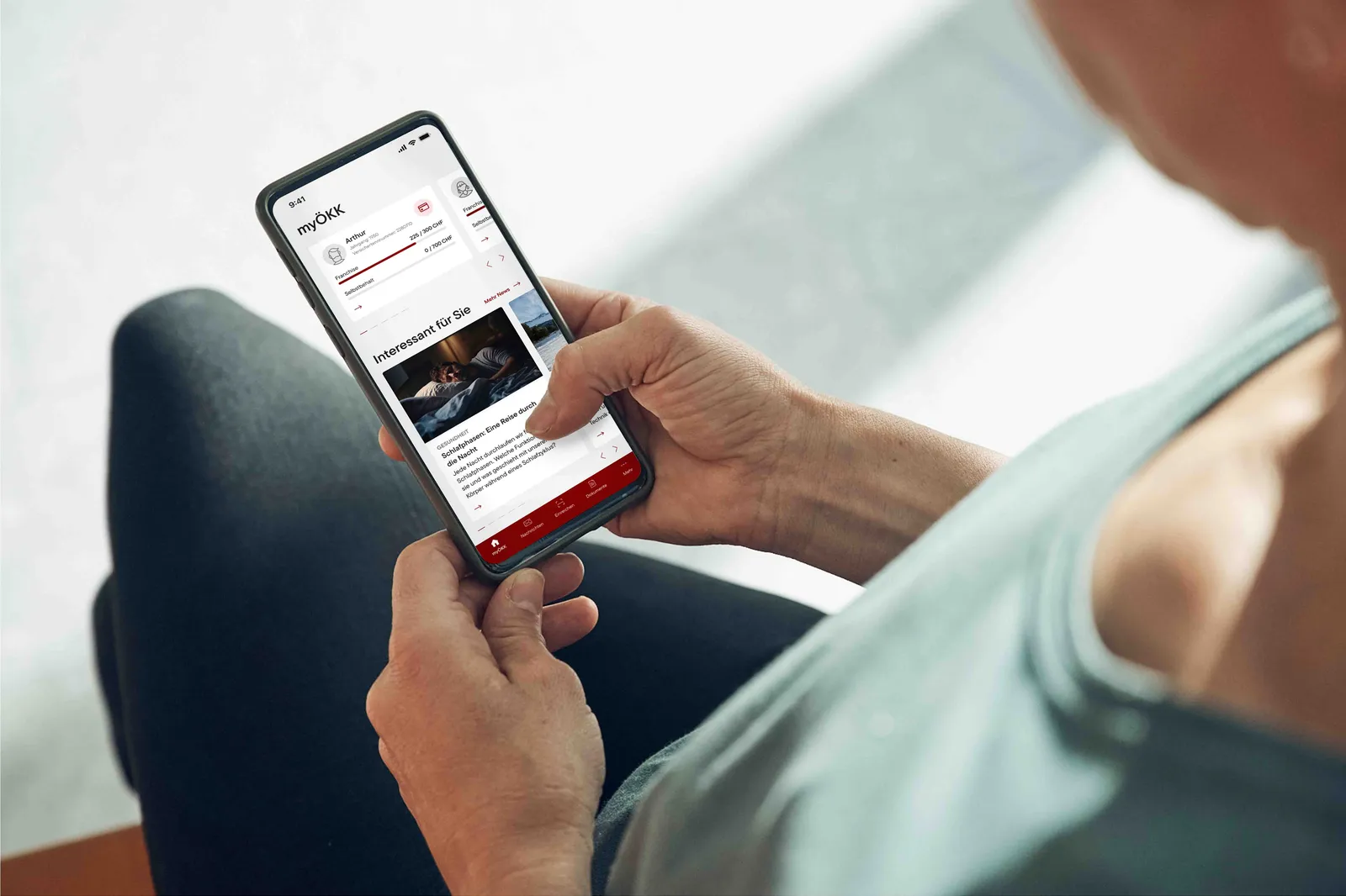 Person holds a smartphone and uses the myÖKK app.