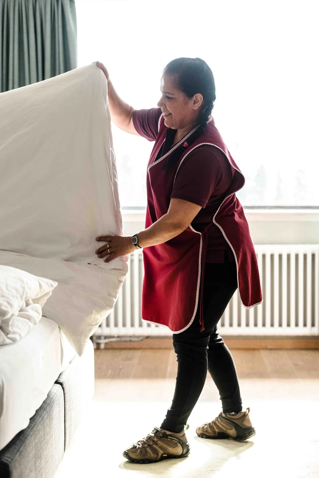 Employée de maison faisant un lit et arrangeant un oreiller