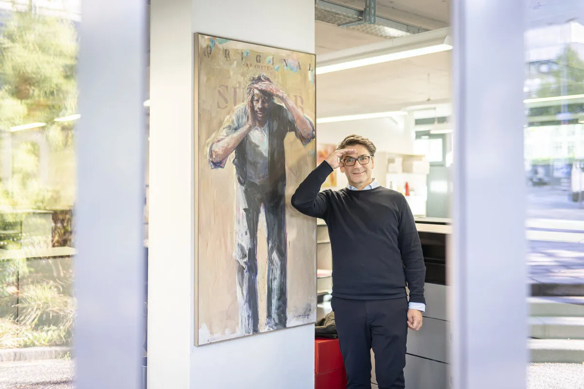 Mann steht in einer Druckerei vor einem Portrait