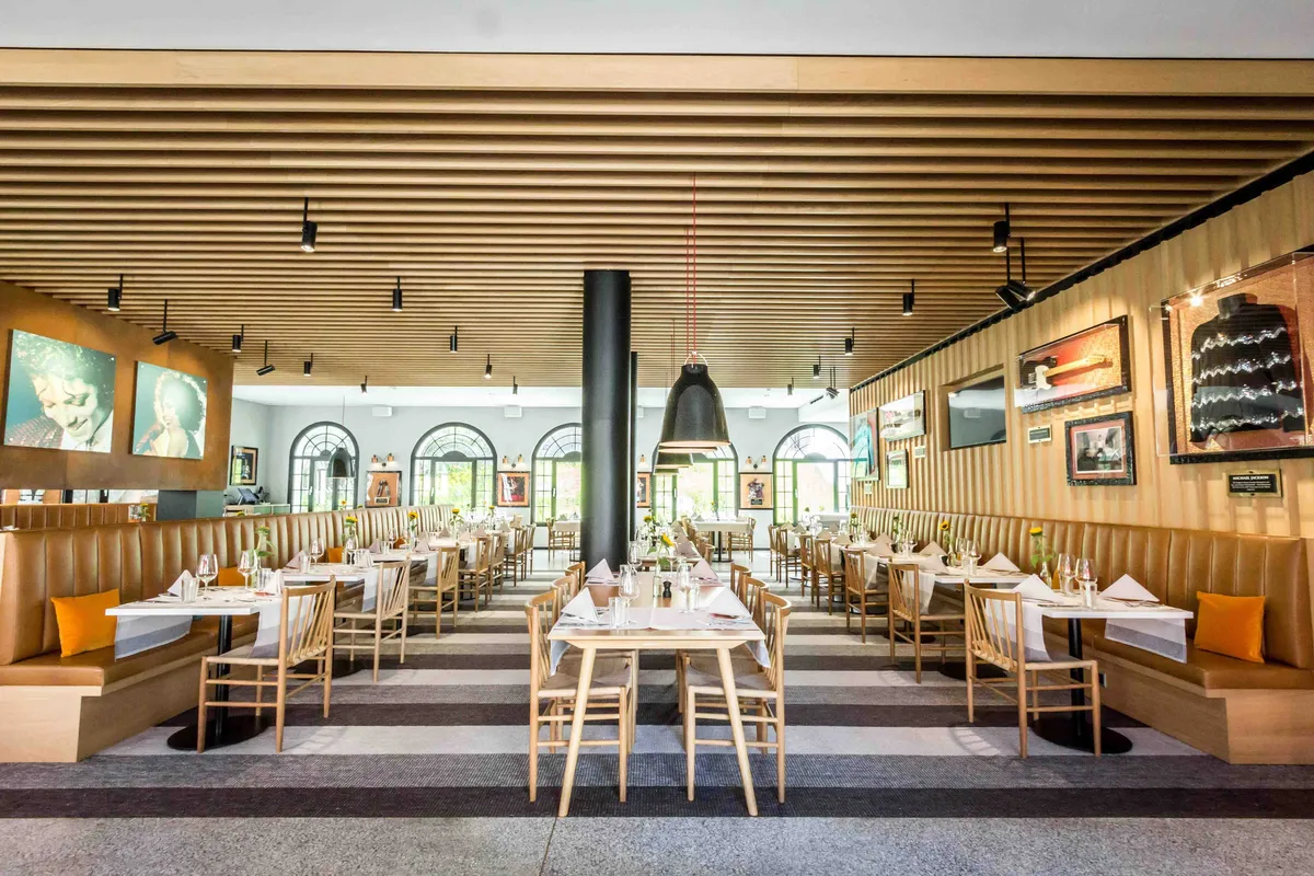 Modern eingerichtetes Restaurant mit geschwungener Sitzbank, grossen Rundbogenfenstern und stilvollem Interior im Hard Rock Hotel Davos.